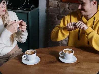 Twee mensen communiceren met gebaren aan een tafel met koffie